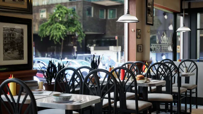 Sunlit corner cafe interior with checker-floor seating and street view